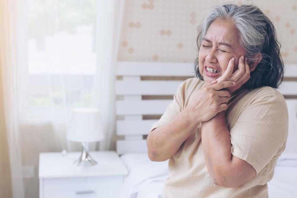 an old woman cupping her jaw due to tooth pain
