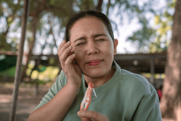 a woman experiencing tooth pain from biting on something hard