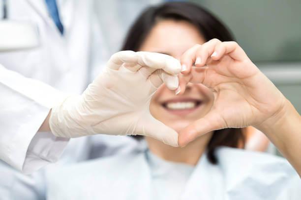 a patient and dentist forming a heart with their hands